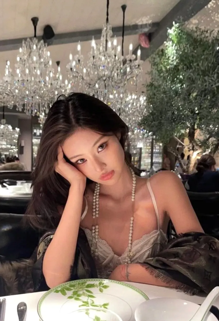 Young woman with long dark hair seated at a table in an elegant restaurant.